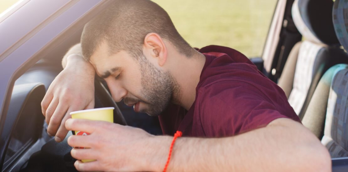 tired unshaven male leans wheel holds paper cup coffee scaled