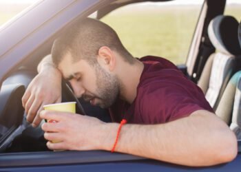 tired unshaven male leans wheel holds paper cup coffee scaled