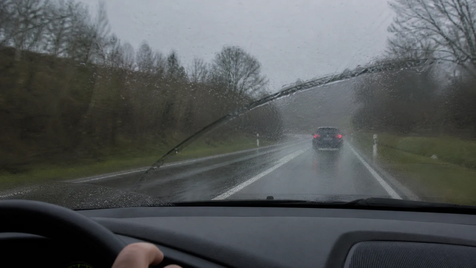 Vue conducteur à travers le pare-brise avec le véhicule devant à bonne distance, jour pluvieux