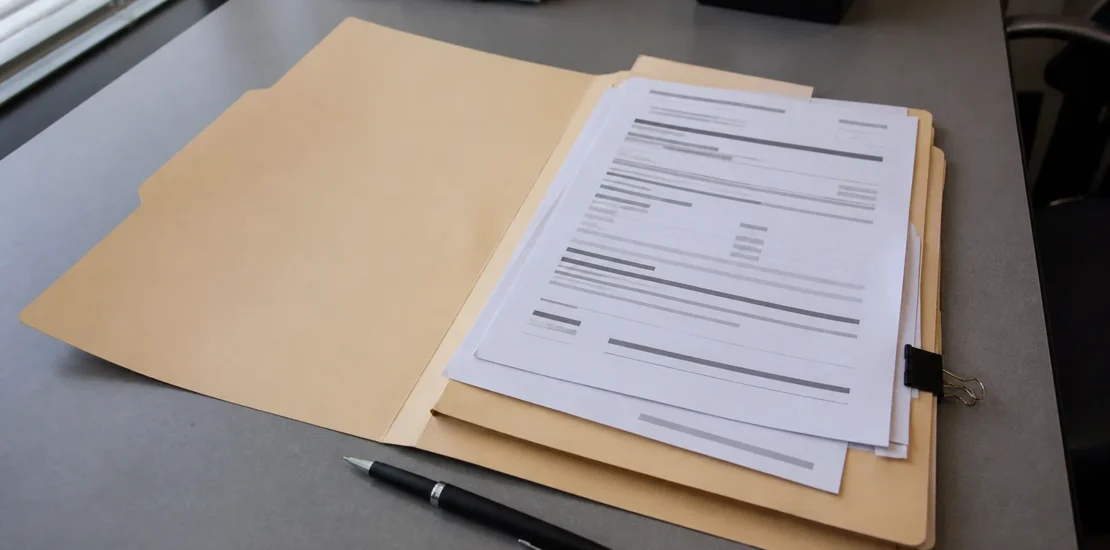 Dossier de résiliation d’assurance auto ouvert sur une table avec un stylo