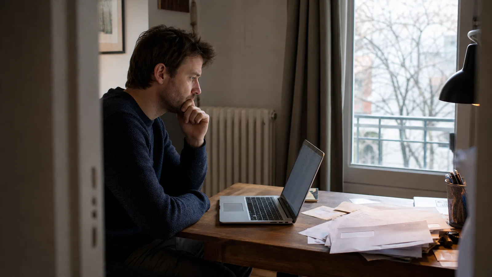 Personne assise à un bureau avec un ordinateur portable, lumière de fenêtre