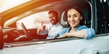 happy young couple chooses buying new car family dealership scaled